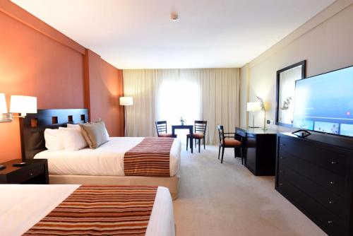 um quarto de hotel com duas camas e uma televisão de ecrã plano em Camberland Resort & Spa Ramallo em Ramallo