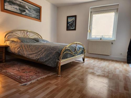 ein Schlafzimmer mit einem Bett, einem Fenster und einem Holzboden in der Unterkunft Le Phisan in Épinal