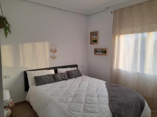 a white bedroom with a large bed and a window at A vora mar in Benicarló