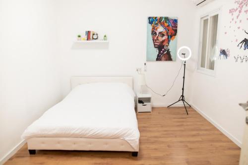 una camera bianca con letto e lampada a pavimento di BrideHousehaifa a Haifa