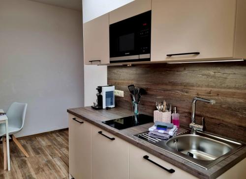 a kitchen with a sink and a microwave at Fritz Aparthotel Potsdam in Potsdam
