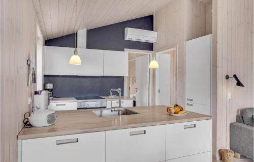 una cocina con armarios blancos y un bol de fruta en la barra en Cozy Home In Nykbing Sj With Wifi, en Nykøbing Sjælland