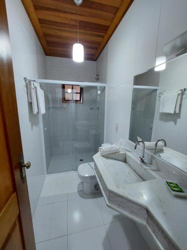 a bathroom with a shower and a sink and a toilet at Pousada Canoa Caiçara Ilhabela in Ilhabela