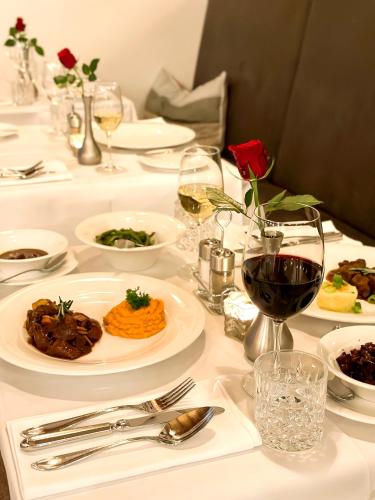 a table with plates of food and glasses of wine at Hotel Achterum Greetsiel in Greetsiel