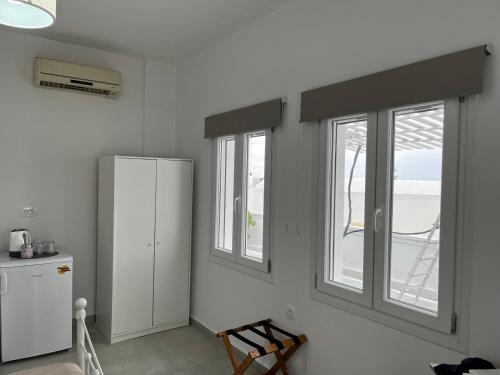 a kitchen with two windows and a white refrigerator at Firaxenia rooms in Fira