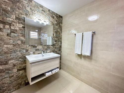 a bathroom with a sink and a stone wall at Lirmar Apartments in Kralendijk