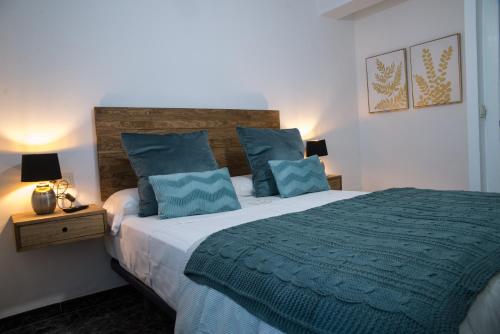 1 dormitorio con 1 cama grande con almohadas azules en Apartamentos MC centro, en Ronda