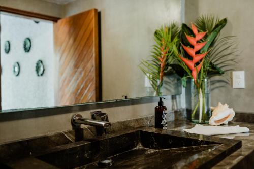 a bathroom sink with a bottle of soap and a mirror at Casa Sirena in Ixtapa