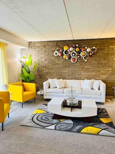 sala de estar con sofá blanco y sillas amarillas en HONORAY-Kes, en Monroeville
