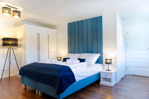 a bedroom with a large bed with a blue headboard at Funaberia -25 hektarowa luksusowa posiadłość z basenem, jacuzzi, sauną, boiskiem wielofunkcyjnym in Skop