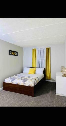 1 dormitorio con 1 cama con cortinas amarillas en HONORAY-Kes, en Monroeville