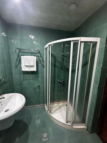 a green bathroom with a shower and a sink at Hotel Ritsa in Batumi