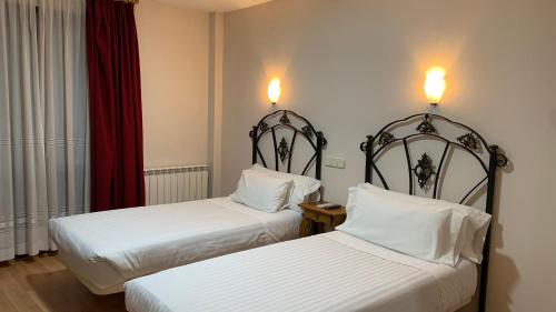 a hotel room with two beds and two lamps at Hotel Posta Real in Sigüenza