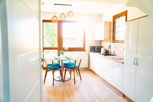 a kitchen with white cabinets and a table and chairs at Promyki - Domy Apartamentowe in Chłopy