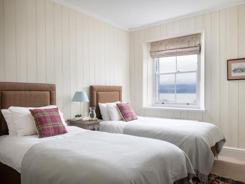 two beds in a white room with a window at Flagstaff in Beaumaris
