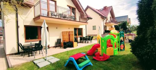 a house with a playground in the yard at Promyki - Domy Apartamentowe in Chłopy