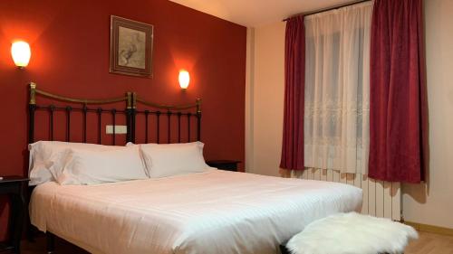 a bedroom with a large bed with red walls at Hotel Posta Real in Sigüenza