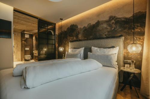 a bedroom with a large white bed with a painting on the wall at Black Eagle Luxury Appartements in Mayrhofen