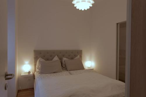 1 dormitorio con 1 cama blanca y 2 lámparas. en Casa Nostra - Moderne Stadtwohnung mit Balkon, en Viena