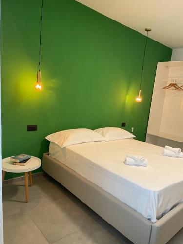 ein grünes Schlafzimmer mit einem Bett und einem Tisch in der Unterkunft Tresino Rooms in Agropoli