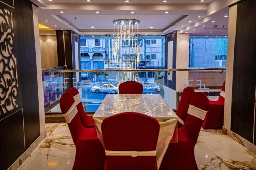 una sala da pranzo con tavolo e sedie e una grande finestra di فندق سرايا المسك Saraya Al Misk Hotel a La Mecca