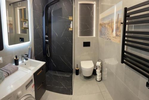 a bathroom with a shower and a toilet and a sink at Apartament Oksywie II in Gdynia