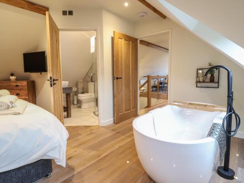 - une grande salle de bains avec une baignoire à côté d'un lit dans l'établissement Tyn Llwyn Barn, à Corwen