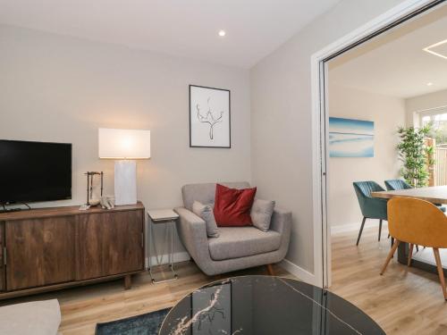 a living room with a chair and a television at Lilac Cottage in Lymington