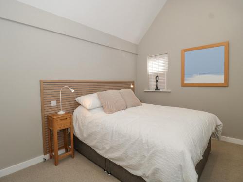 a bedroom with a bed and a lamp on a table at Lilac Cottage in Lymington