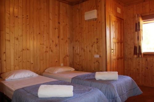 2 camas en una habitación con paredes de madera en Rocaplana Club de Campo, en Vilarrodona