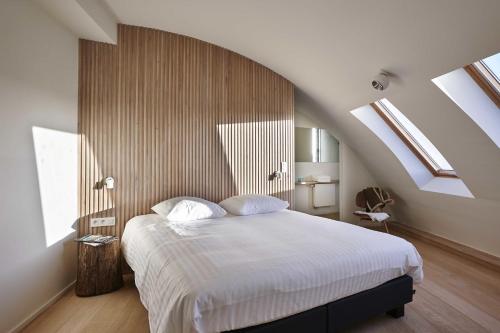 Schlafzimmer mit einem Bett mit weißer Bettwäsche und Oberlichtern in der Unterkunft Kustappartementen in Blankenberge