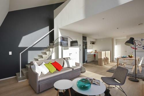 a living room with a gray couch and a staircase at Kustappartementen in Blankenberge