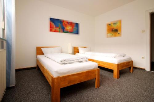 two beds in a room with white sheets at Am Apfelgarten-2 Apartments mit eigenem Parkplatz-Flörekeweg in Lüneburg