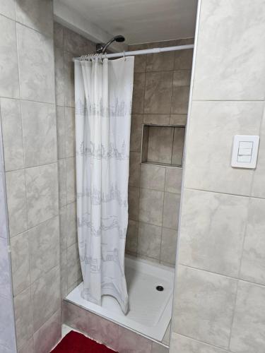 y baño con ducha con cortina blanca. en ALAKALUFES House en Ushuaia