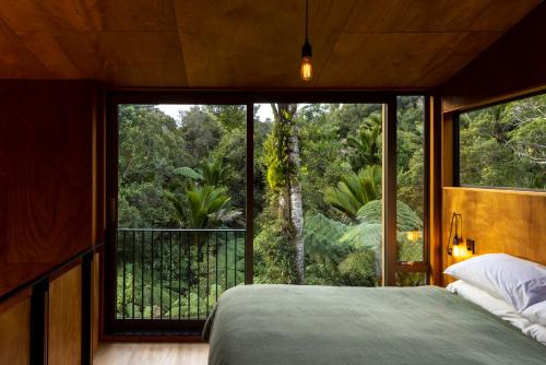 a bedroom with a bed and a large window at Punakaiki Forest Retreat in Punakaiki