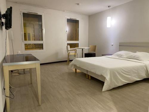 a bedroom with a bed and a desk and a sink at Appartement Avenue de la Gare in Lourdes