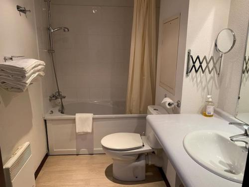 a bathroom with a toilet and a sink and a tub at Appartement Avenue de la Gare in Lourdes