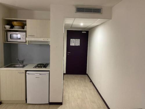 a small kitchen with a black door and a microwave at Appartement Avenue de la Gare in Lourdes