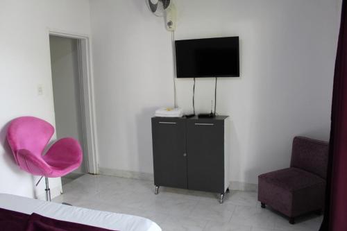a room with a tv and a pink chair at Finca Hotel San Angello in Quimbaya