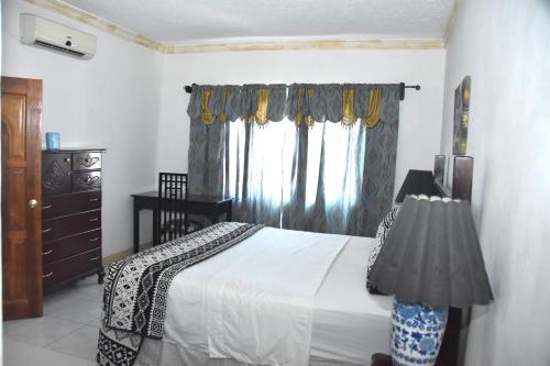 a bedroom with a bed and a dresser and a window at Embassy Deluxe apartment in Kingston