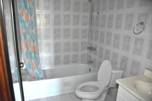 a bathroom with a toilet and a tub and a sink at Embassy Deluxe apartment in Kingston