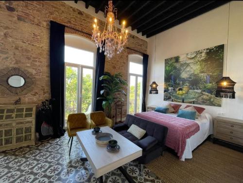 a bedroom with a bed and a couch and a table at Atelier Art & Suite in Ayamonte