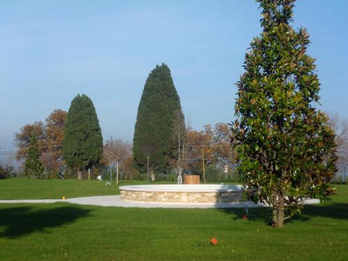 a park with trees and a fountain in the grass at Postiglione Country House in Cingoli