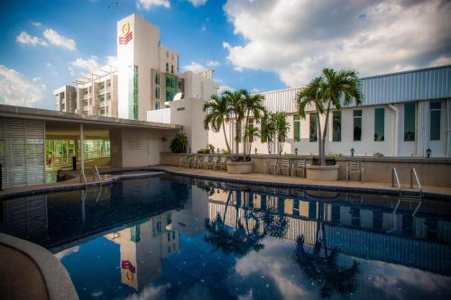 a swimming pool in front of a building with palm trees at Golden City Rayong Hotel - SHA Extra Plus Certified in Rayong