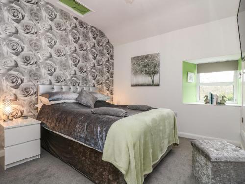 1 dormitorio con 1 cama grande con una pared cubierta de rosas en The Hideaway en Chacewater