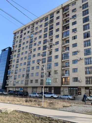 duży budynek z samochodami zaparkowanymi przed nim w obiekcie Magistral w mieście Biszkek