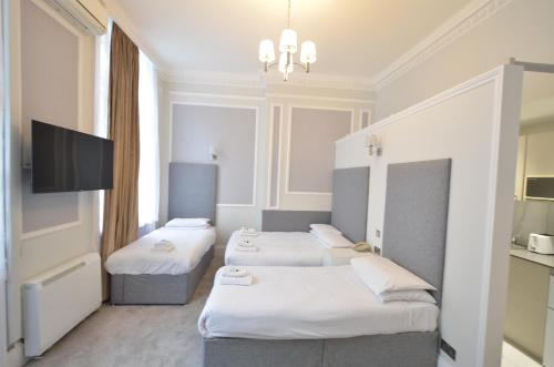 a hotel room with three beds and a flat screen tv at Amber Residence Aparthotel in London