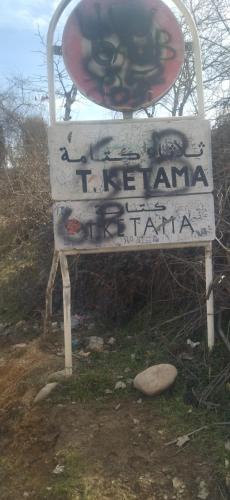 a sign with graffiti on it sitting in the grass at Tlata ketama in Ketama