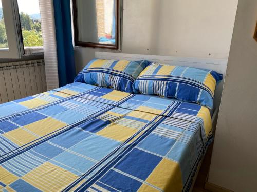 Bett mit blauer und gelber Bettwäsche und Kissen in der Unterkunft Apartment Alina in Cadegliano Viconago
