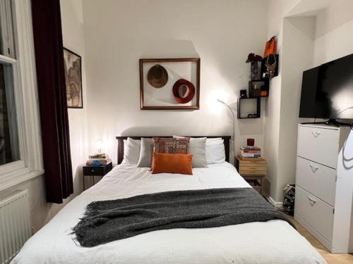 a bedroom with a bed with a black blanket on it at Lovely flat near Holland Park in London